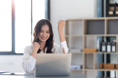 Beautiful asian woman using laptop computer, exciting and celebrating with good news of business successful. Small business startup concept...