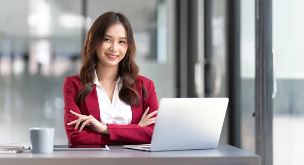 Portrait of smiling beautiful business asian woman in pink suit working in home office desk using computer. Business people employee freelance online marketing e-commerce, work from home concept..