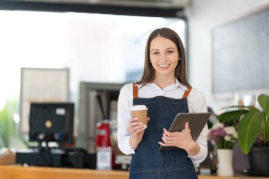 Küçük bir iş kuran, bir bar tezgahının yanında duran önlüklü mutlu Asyalı kadın, küçük işletme sahibi, restoran sahibi, barista, cafe, Online, KME, girişimci ve satıcı konsepti..