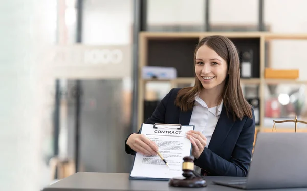 Attractive young lawyer in office Business woman and lawyers discussing contract papers with brass scale on wooden desk in office. Law, legal services, advice, Justice and real estate concept...