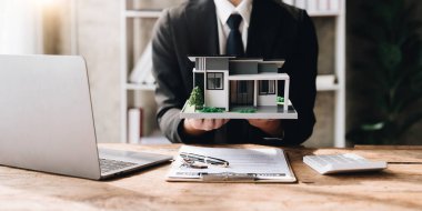 İş adamı, satıcı ev ve ev modelini tutacak. Artan grafik veya fiyat tahminlerinin grafiğini de dahil et. Satılık, yatırım için. Değer, gelir, servet, varlık, gayrimenkul ve mülk kavramı