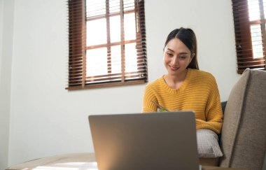 People relax at home and wellness lifestyle. Young adult asian woman eating salad and using laptop computer for watching online movie on internet...