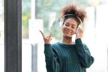 Kulaklık ve dijital tabletle müzik dinleyen gülümseyen zenci bir kadının portresi...