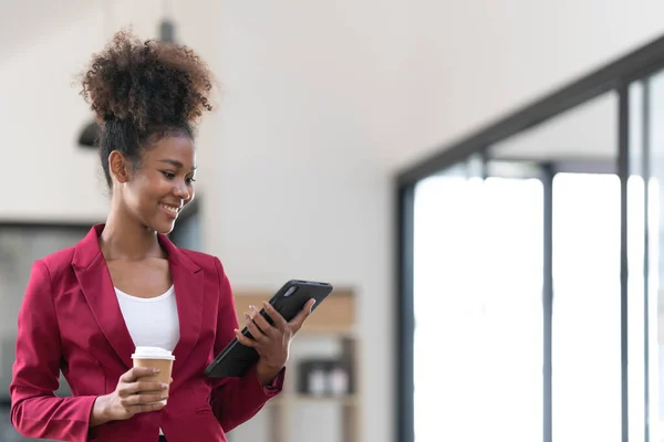 Portrait of smart afro young entrepreneur woman using her digital tablet while standing looking at camera in the office.
