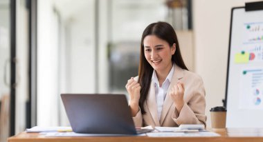 Pretty Asian businesswoman sitting on a laptop And the work came out successfully and the goal was achieved, happy and satisfied with her...