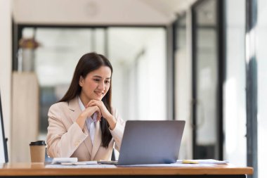 Ofiste dizüstü bilgisayarda çalışan genç bir kadın. Ofisteki iş yerinde oturan Asyalı iş kadını. Güzel Freelancer Kadını evinde çalışıyor.