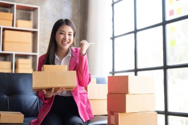 Startup SME small business entrepreneur of freelance Asian woman using a laptop with box Cheerful success happy Asian woman her hand lifts up online