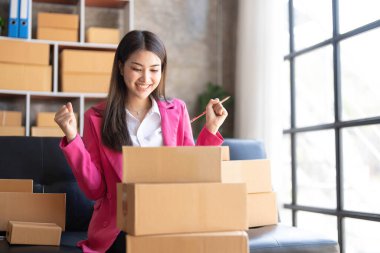 Startup SME small business entrepreneur of freelance Asian woman using a laptop with box Cheerful success happy Asian woman her hand lifts up online