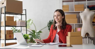 Girişimci elinde kalemle hesap makinesi kullanıyor, ev ofisinin mali giderlerini hesaplıyor, çevrimiçi pazar paketleme kutusu teslimatı, başlangıçta başarılı küçük işletme sahibi KME, konsept..