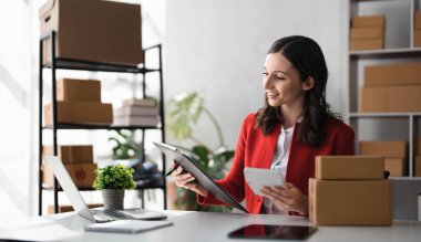 Girişimci elinde kalemle hesap makinesi kullanıyor, ev ofisinin mali giderlerini hesaplıyor, çevrimiçi pazar paketleme kutusu teslimatı, başlangıçta başarılı küçük işletme sahibi KME, konsept..