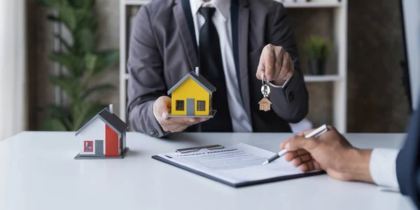 Real estate agent is discussing and explaining the terms of the home purchase contract. Businessman signing a contract agreement, mortgage, rent, lease, home insurance...