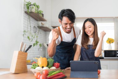 Romantik Çift mutfak yemek pişiriyor. Yakışıklı ve çekici genç kadın birlikte salata yaparken eğleniyor musun. Sağlıklı yaşam konsepti...