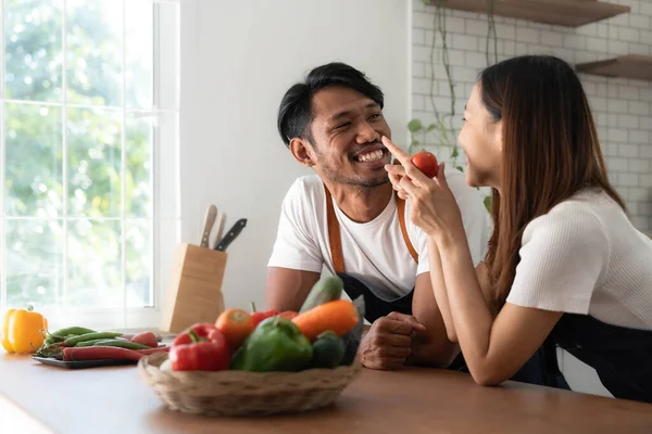 Romantic couple is cooking on kitchen. Handsome man and attractive young woman are having fun together while making salad. Healthy lifestyle concept...
