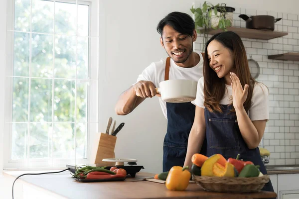 Romantic couple is cooking on kitchen. Handsome man and attractive young woman are having fun together while making salad. Healthy lifestyle concept...