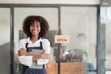 Startup successful small business owner sme beauty girl stand with tablet smartphone in coffee shop restaurant. Portrait of asian tan woman barista cafe owner SME entrepreneur seller business concept