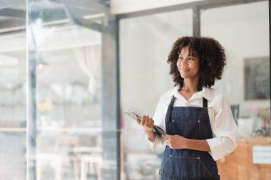 Startup successful small business owner sme beauty girl stand with tablet smartphone in coffee shop restaurant. Portrait of asian tan woman barista cafe owner SME entrepreneur seller business concept