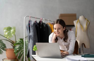Yeni kadın ile Bayan Giyim Tasarımcısı çalışma giymek rahat atölye stüdyo, moda tasarımcısı, dokunma, eller el yapımı giyimleri içinde tutan giysiler raf ayakta terzi koleksiyonu