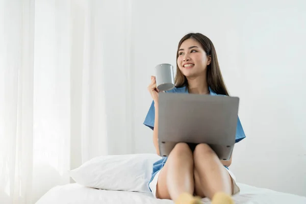 Happy, Relaxing Young beautiful Asian female watching movie or series on notebook in emotional smile happily while laying on the bed in her bedroom. Day off, Chill out and leisure concept...