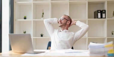 Yapılan işten memnun. Ofisinde çalışırken dizüstü bilgisayarda çalışan mutlu genç adam...