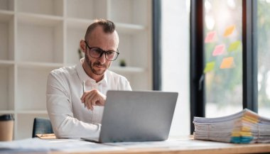 Businessman using laptop computer in office. Happy middle aged man, entrepreneur, small business owner working online...