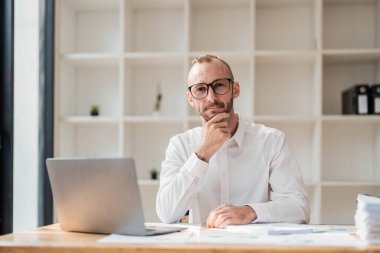 Businessman using laptop computer in office. Happy middle aged man, entrepreneur, small business owner working online...