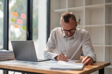 Businessman using laptop computer in office. Happy middle aged man, entrepreneur, small business owner working online...