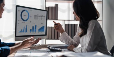 İki iş adamı toplantı odasında proje stratejisi hakkında konuşuyor. İş adamı, mali veri raporu hakkında sohbet ve tavsiyelerde bulunurken, modern işyerindeki iş arkadaşıyla proje planlamasını tartıştı