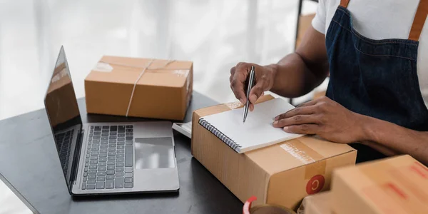 Asian business men use laptop computer checking customer order online shipping boxes at home. Starting Small business entrepreneur SME