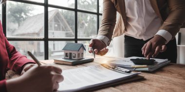 Emlakçı ve müşteriyle ev modeli satın alma, sigorta ya da kredi alma ya da emlak ya da mülkiyet sözleşmesi hakkında tartışıyor....