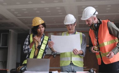 İnşaat mühendisi takımları modern kentteki inşaat sahasında birlikte çalışan işçi kaskı takıyorlar. Foreman Endüstri Mühendislik Mühendisliği ekip çalışması. Asya endüstrisi profesyonel takımı...