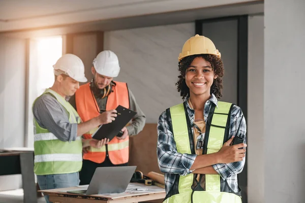 Leadership Concept by Female Engineers : Portrait of a happy female engineer in front of a group of male construction workers : Effective teamwork..