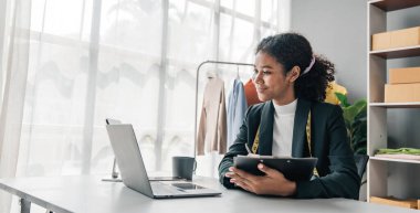 Portre gülüşü siyah kadın terzide elbise üzerinde çalışıyor. Atölyede yeni el yapımı takım elbiseler dikme başarısından sonra çekici, genç bayan moda tasarımcısı gülümsemesi....