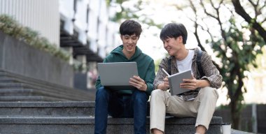 Mutlu Asyalı üniversite öğrencisi arkadaşıyla cep telefonuyla oyun oynuyor...