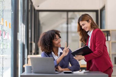 İki iş adamı toplantı odasında proje stratejisi hakkında konuşuyor. İş adamı, mali veri raporu hakkında sohbet ve tavsiyelerde bulunurken, modern işyerindeki iş arkadaşıyla proje planlamasını tartıştı