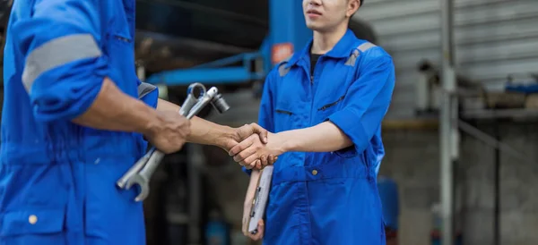 stock image Two car mechanic team shaking hand at automobile service center. Repair service concept. Car repair and maintenance. Car mechanic working at automotive team service center..