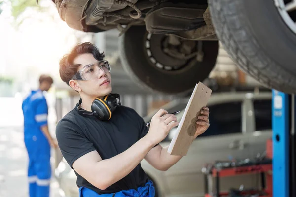 stock image car service, repair, maintenance and people concept - happy smiling auto mechanic man or smith with clipboard at workshop..