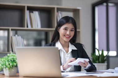 İş kadını, ofis ve iş geçmişinde, vergi, muhasebe, istatistik ve analitik araştırma kavramında matematik finansmanı için hesap makinesi kullanıyor.