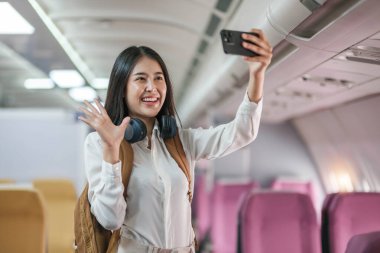 Asyalı bir kadının portresi. Ekonomi sınıfı bir uçuşu beklerken selfie çekiyor ya da anılarını yakalıyor. Seyahat konsepti, tatiller, turizm..