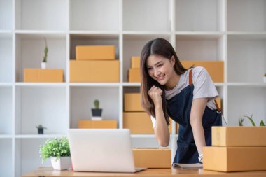 Mutlu Asyalı genç girişimci, internet üzerinden alışveriş merkezinden gelen siparişleri kontrol ettikten sonra satış başarısı için gülümse, internet üzerinden ticaret ve eTicari ticaret kavramı...