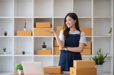 Mutlu Asyalı genç girişimci, internet üzerinden alışveriş merkezinden gelen siparişleri kontrol ettikten sonra satış başarısı için gülümse, internet üzerinden ticaret ve eTicari ticaret kavramı...