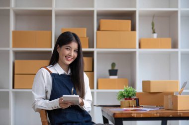 Startup small business entrepreneur SME, asian woman packing cloth in box. Portrait young Asian small business owner home office, online sell marketing delivery, SME e-commerce telemarketing concept