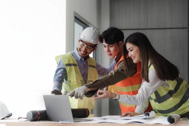 Mühendisler mimari planları olan bir takım olarak çalışırlar. İnşaat projesi konseptini mimar ekipmanlarıyla çizen mühendis masa başında konuşan mimarlar ve inşaat konsepti.