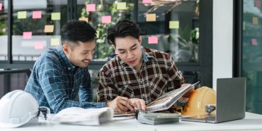 İnşaat mühendisi takımları modern kentteki inşaat sahasında birlikte çalışan işçi kaskı takıyorlar. Foreman Endüstri Mühendislik Mühendisliği ekip çalışması. Asya endüstrisi profesyonel takımı...