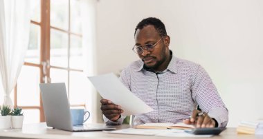 Ofis masasında dizüstü bilgisayarda çalışan yakışıklı Afrikalı siyahi iş adamının portresi....