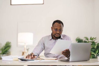 Ofis masasında dizüstü bilgisayarda çalışan yakışıklı Afrikalı siyahi iş adamının portresi....
