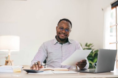 Ofis masasında dizüstü bilgisayarda çalışan yakışıklı Afrikalı siyahi iş adamının portresi....