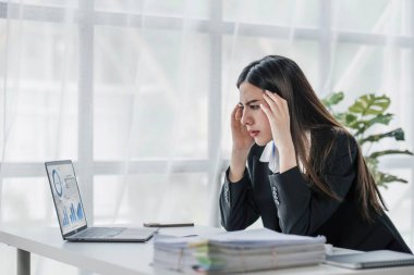 Asyalı bir kadın online problem çözümü hakkında çok endişeli. Laptop ekranına bakıyor. Asyalı ciddi iş kadını zor bir bilgisayar işini çözmeye odaklanmış....