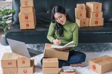 Startup small business entrepreneur SME, asian woman packing cloth in box. Portrait young Asian small business owner home office, online sell marketing delivery, SME e-commerce telemarketing concept