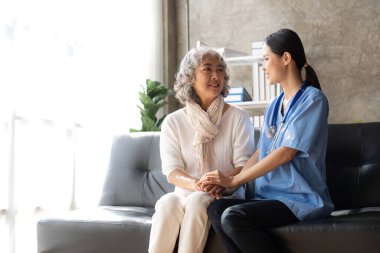 Asyalı yaşlı kadın hasta bakımevindeki hekim hemşireye danışıyor...