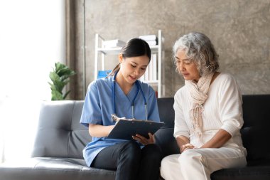 Asyalı yaşlı kadın hasta bakımevindeki hekim hemşireye danışıyor...